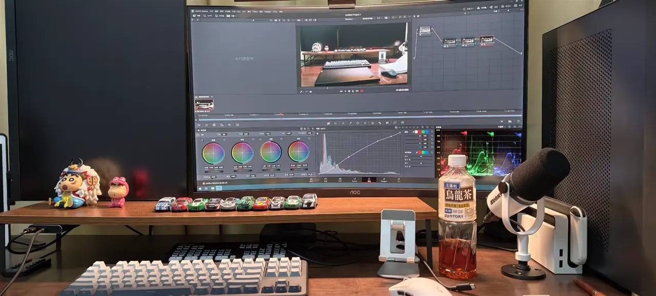 A home studio desk with a microphone, editing software, and small collectibles